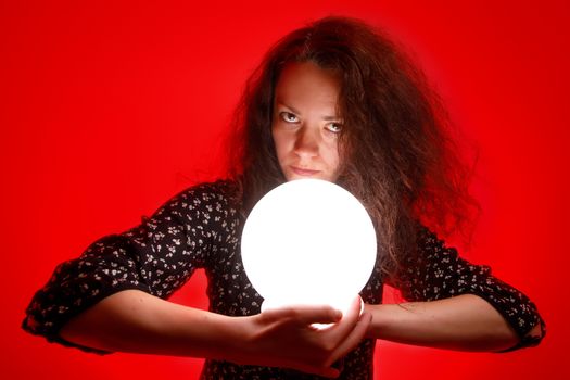 Fortuneteller holding a glowing ball in her hands. Red background