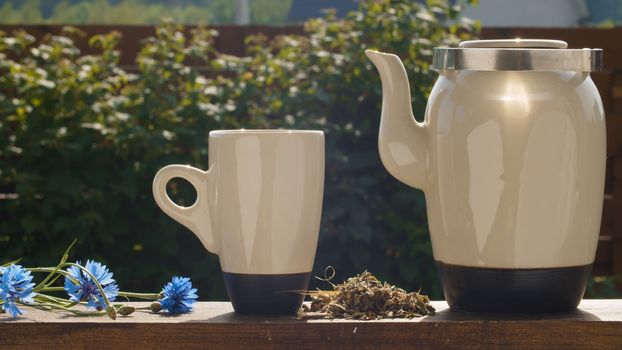 Close up teacup and teapot on the table in the garden at summer day