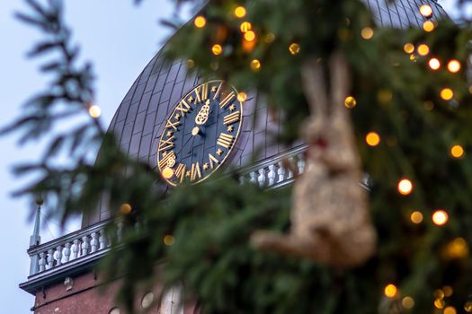 Clock in church tower. In the foreground Christmas decorations and lights.