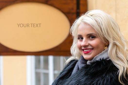 Young, smiling, blond woman at the signboard with free space for text - image
