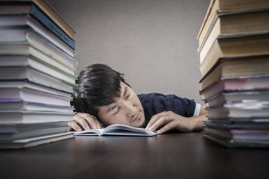 The young man sleep on a table between textbooks