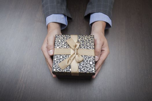 Man's hands keep a box in a business suit wrapped up by a bow