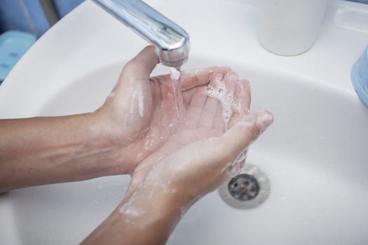 We wash hands with soap under a water stream