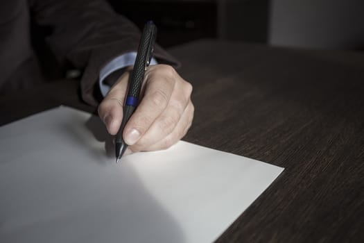 Man's hands keep the handle in a business suit over a sheet of paper