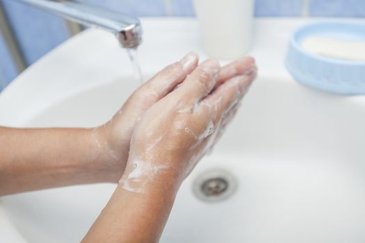 We wash hands with soap under a water stream