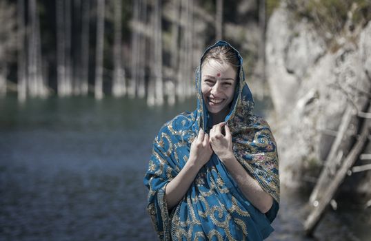 The girl of the European appearance laugh and poses in the Indian sari at Kaindy lake