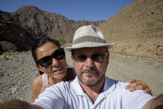 A couple in the 40s taking a selfie in a Wadi (dry riverbed) in the United Arab Emirates.