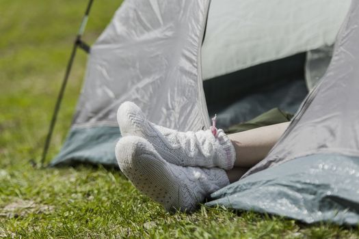 Female feet in warm socks stick out of tent