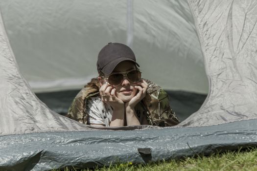 The girl looks out of tent and has a rest