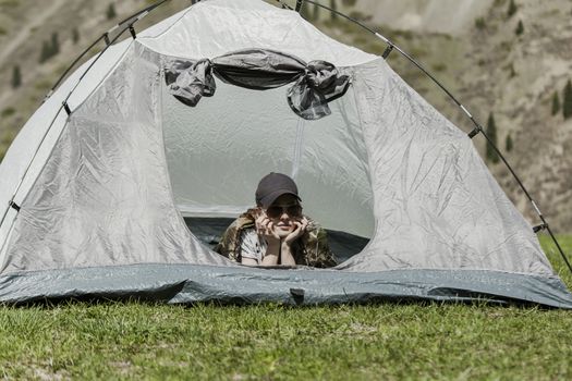 The girl looks out of tent and has a rest