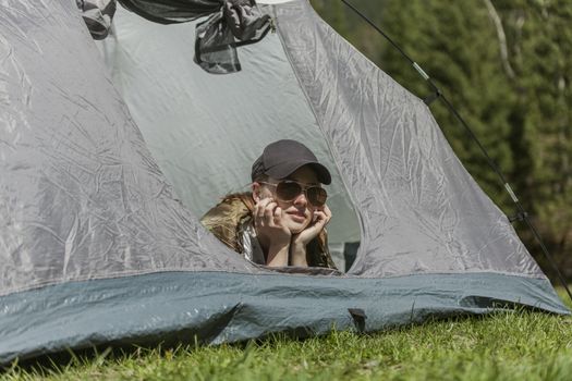 The girl looks out of tent and has a rest