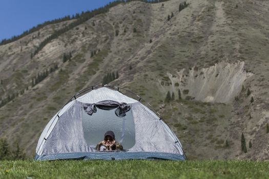 The girl looks out of tent and has a rest