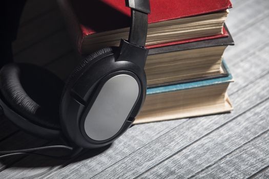 The book, big earphones lie on a wooden background, audiobooks