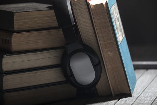 The book, big earphones lie on a wooden background, audiobooks