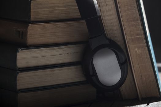 The book, big earphones lie on a wooden background, audiobooks