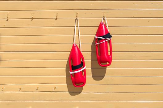 Two red rescue buoys on the wall on the pier. lifeguard tower with orange buoy on the beach. Rescue buoy on the rescue post.