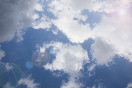 Blue sky with white clouds, sun and lens flare effect