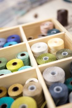 Lifestyle concept, work from home to reinvent your life: close-up detail some colored thread spools in a wooden organizer box with compartments