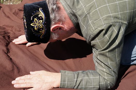 Muslim man performs prayer in nature on a sunny day