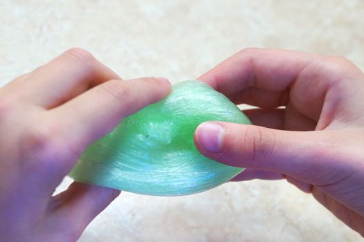 children's hands play with green slime close up