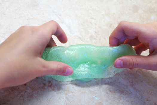 children's hands play with green slime close up