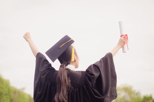 Graduate put her hand up and celebrating with certificate in her hand and feeling so happiness in success of education