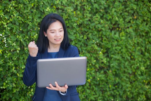 businesswoman holding computer notebook and showing thumb up making the ok gesture.