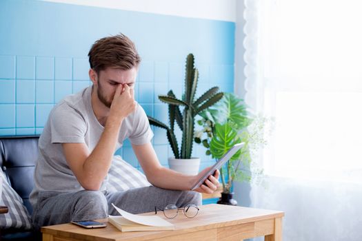 Young man reading book on sofa in the living room.