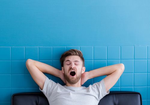 man yawning and going asleep in his  living room