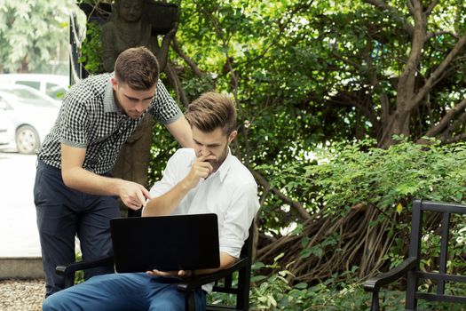 Two business people use of the notebook computer at outdoor.