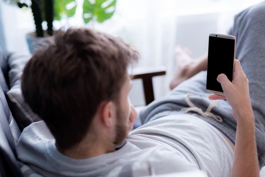 Happy man watching media content in a mobile sitting on a couch at home - Top side view mock up.