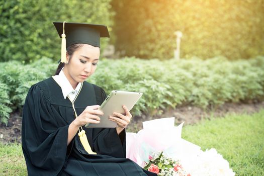 Graduate playing tablet in her hand feeling relaxing and so happiness in commencement day and search job new