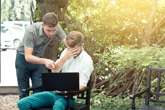 Two business people use of the notebook computer at outdoor.