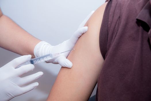 Close-up Of Doctor Injecting Patient With Syringe To Collect Blood