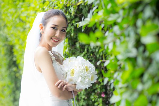 beautiful young woman on wedding day in white dress in the tree wall. Female portrait in the park - Selective focus
