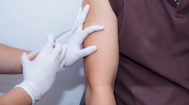 Close-up Of Doctor Injecting Patient With Syringe To Collect Blood