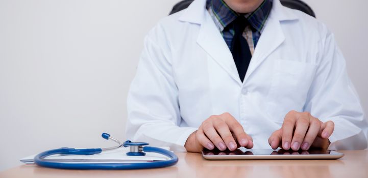 male doctor with tablet computer and stethoscope at the desk on white background.