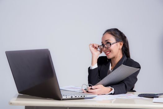 Businesswoman sitting at desk and hand holding glasses in office. 