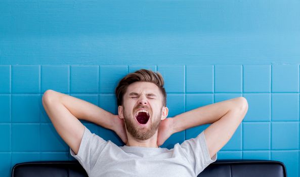 man yawning and going asleep in his  living room