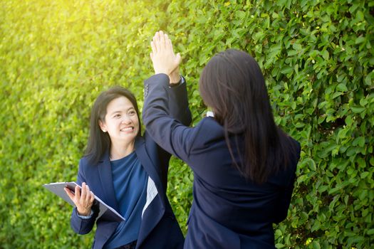 Businesswoman two people high fiving outdoors nature background.