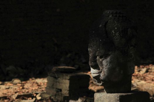 The head of an old Buddha statue, traces of erosion on the ground