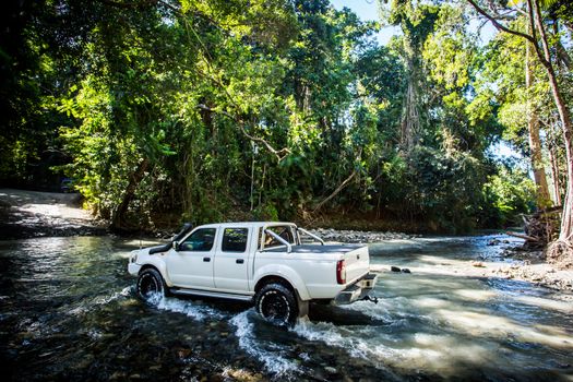 A car drives along Cape Tribulation Rd and crosses a river near Cape Tribulation in the Daintree, Queensland, Australia