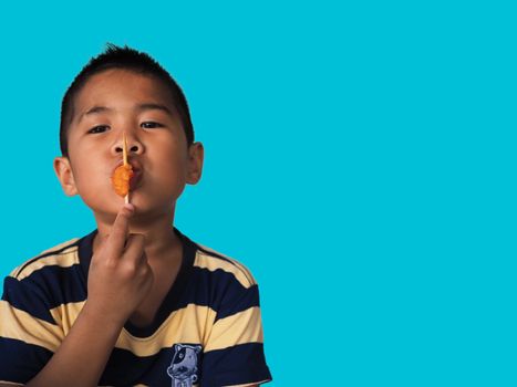 Portrait of a boy eating a hot dog Isolated from on the blue background. clipping path. Junk food concept.
