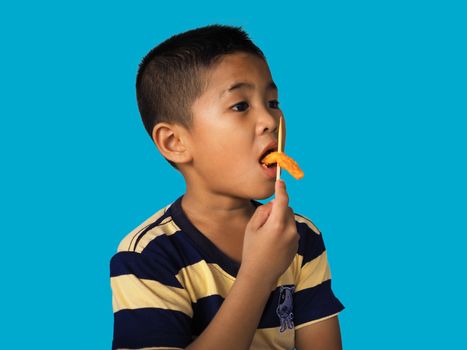 Portrait of a boy eating a hot dog Isolated from on the blue background. clipping path. Junk food concept.