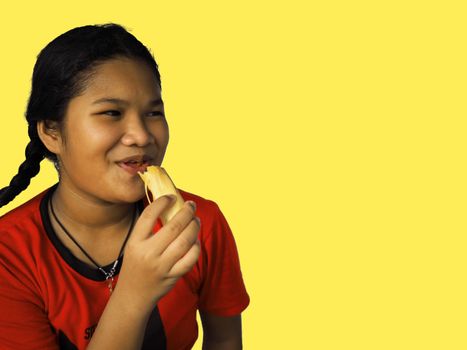 The girl eats hot dog Happily Isolated on a yellow background.
Embed clipping path.
Junk food concept.