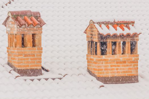 the snowflakes come down thick and cover the chimneys of a house