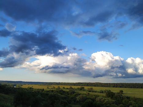 Dark blue and white clouds over the fields and the river, smart