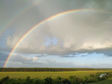 Rainbow and clouds over fields and river, smart.