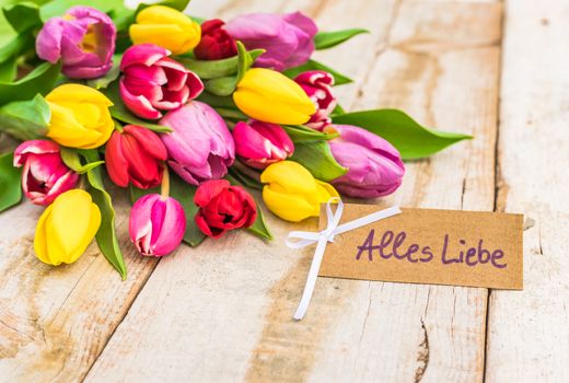 Beautiful bouquet of flowers with greeting card with german text, Alles Liebe, means love