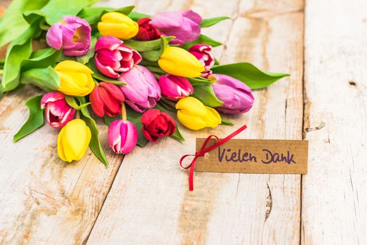 Multicolored bouquet of flowers and label with german text, Vielen Dank, means thank you